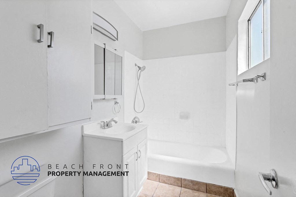 A white bathroom with a shower and a sink.